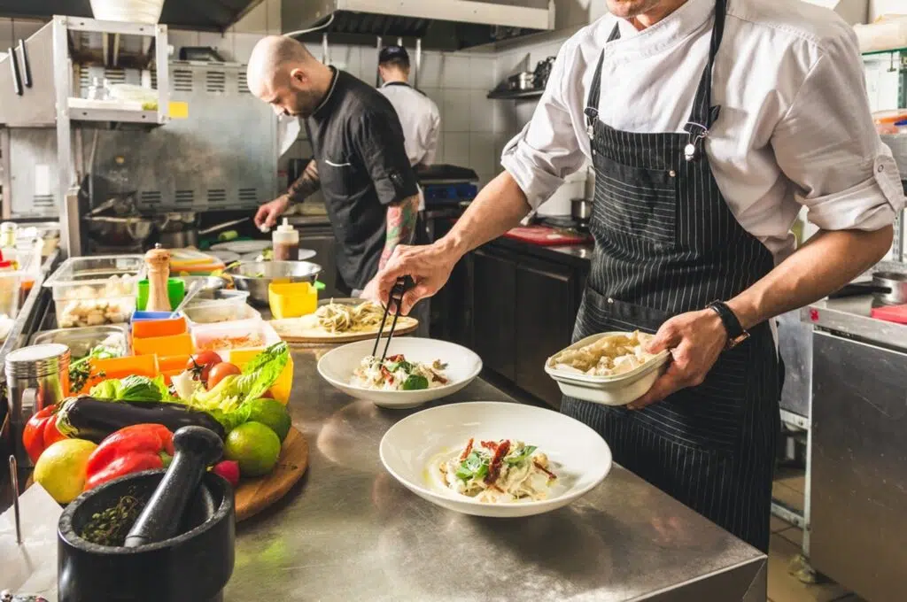 Des cuisiniers dressent des assiettes